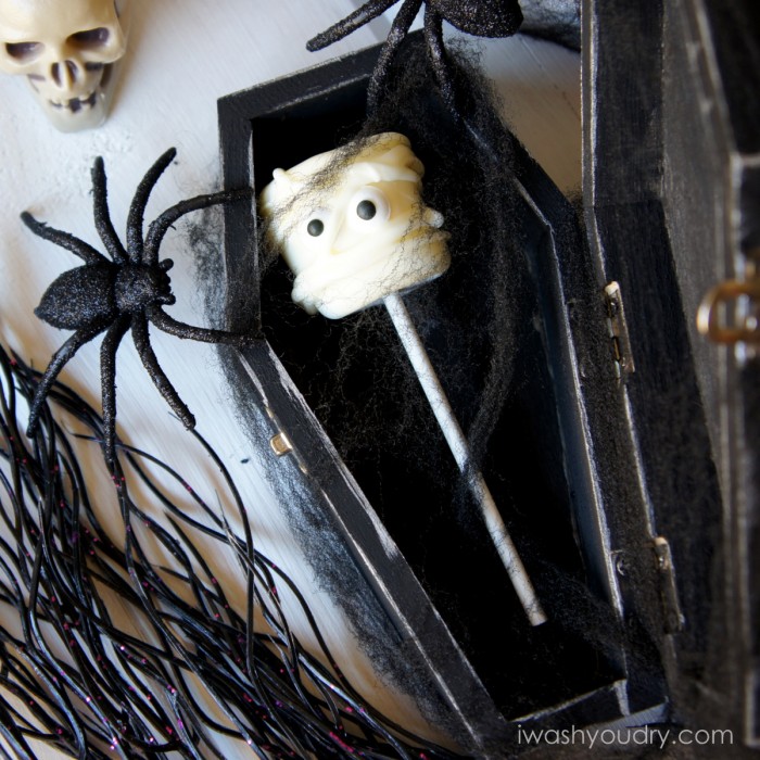 A display of a Mummy themed marshmallow pop in a coffin surrounded by other Halloween decorations