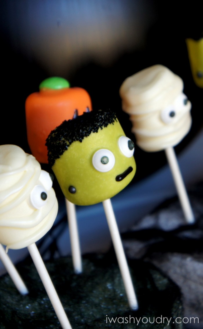 A close up side view of Halloween themed Marshmallow pops - a mummy, a pumpkin, Frankenstein and another mummy