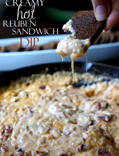 A hand dipping a chip into a dip titled, "Creamy Hot Reuben Sandwich Dip"