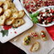 A close up of food on a table, with a tray of toasted baguette slices next to a tray of toppings and three Crostinis on a napkin