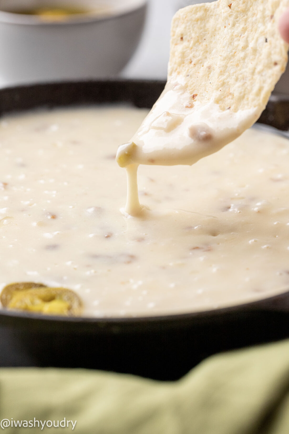 chips dipping into white cheese sauce with sausage chorizo.