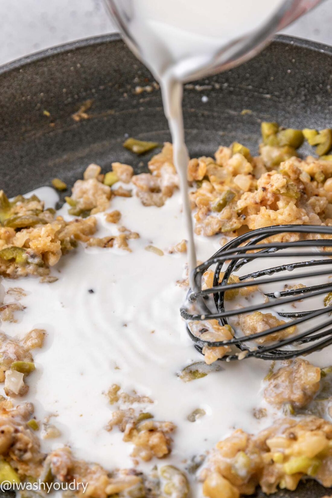 Pouring milk into pan of chorizo and onion. 