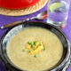 A close up of a bowl of soup topped with cheese and chives