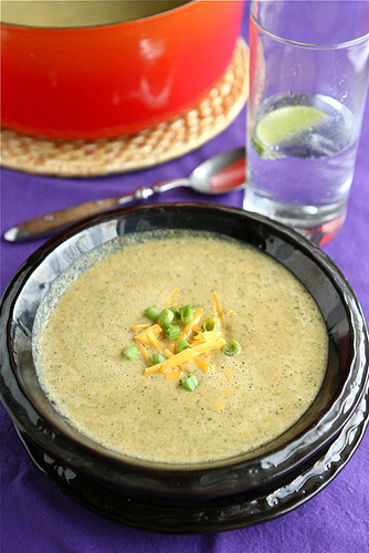 A close up of a bowl of soup topped with cheese and chives