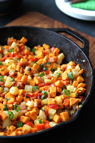 A close up of a pan of sweet potato hash with Canadian Bacon and vegetables