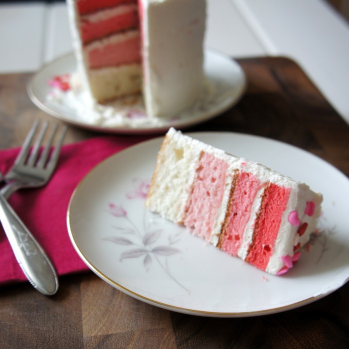 A slice of four layer cake on a plate next to the full cake it was removed from