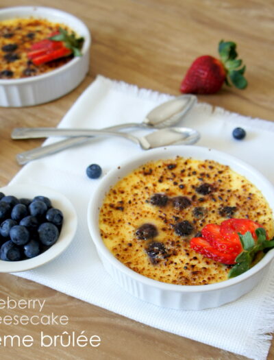 A bowl of Blueberry Cheesecake Creme Brûlée displayed on a table next to a bowl of blueberries