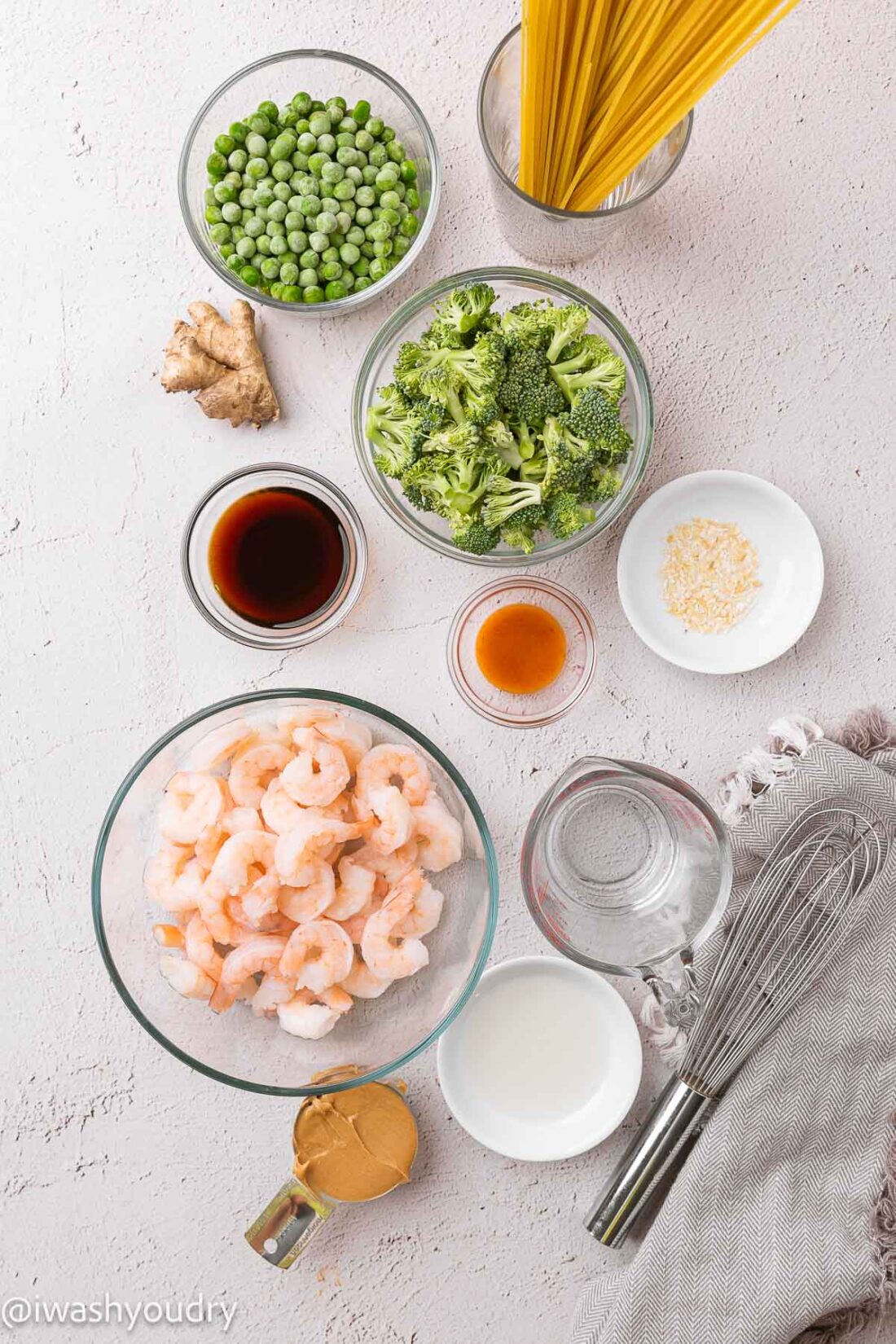 ingredients for pad thai on white surface with shrimp and noodles.