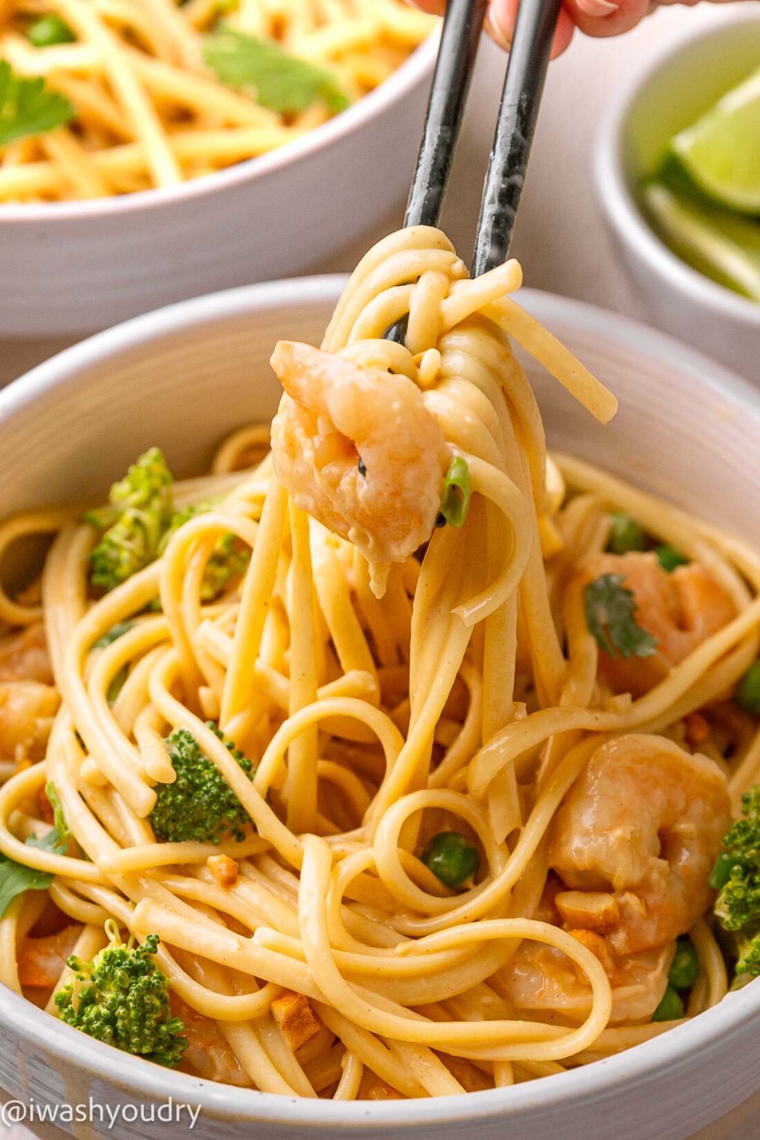 chopsticks full of noodles in peanut sauce with shrimp.