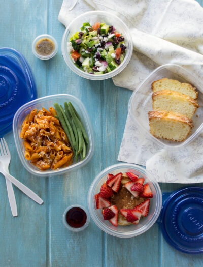 Plastic containers with healthy lunch options displayed on a wooden surface