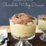 A clear glass dessert cup with Peanut Butter Pudding topped with chocolate whip cream