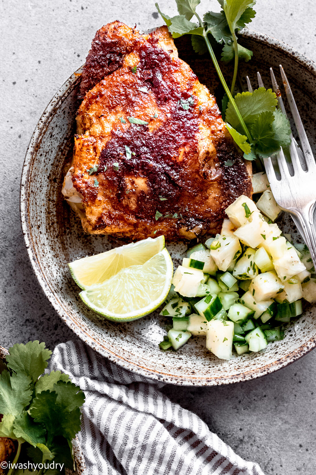 Cooked chili lime chicken thighs on plate with pineapple cucumber salad. 