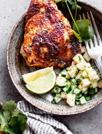 Cooked chickli lime chicken thighs on plate with pineapple cucumber salsa.