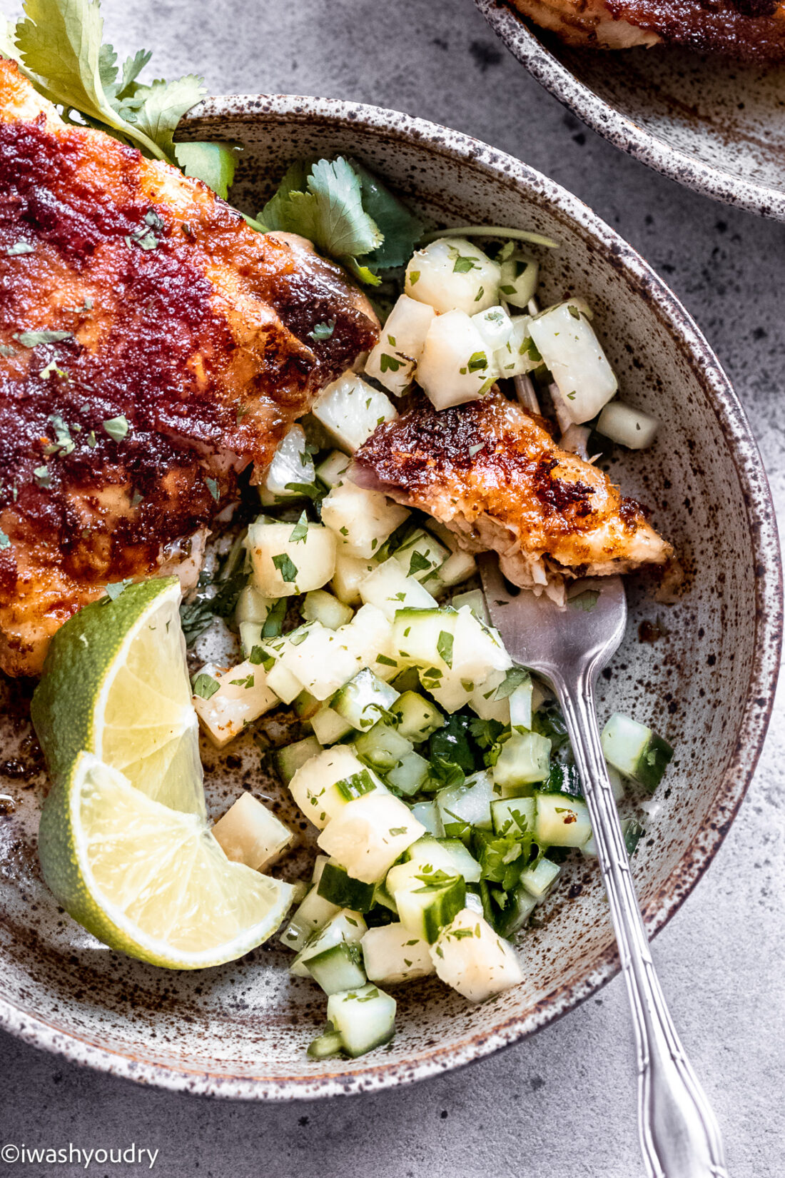 Cooked chili lime chicken with pineapple cucumber salad on gray plate.