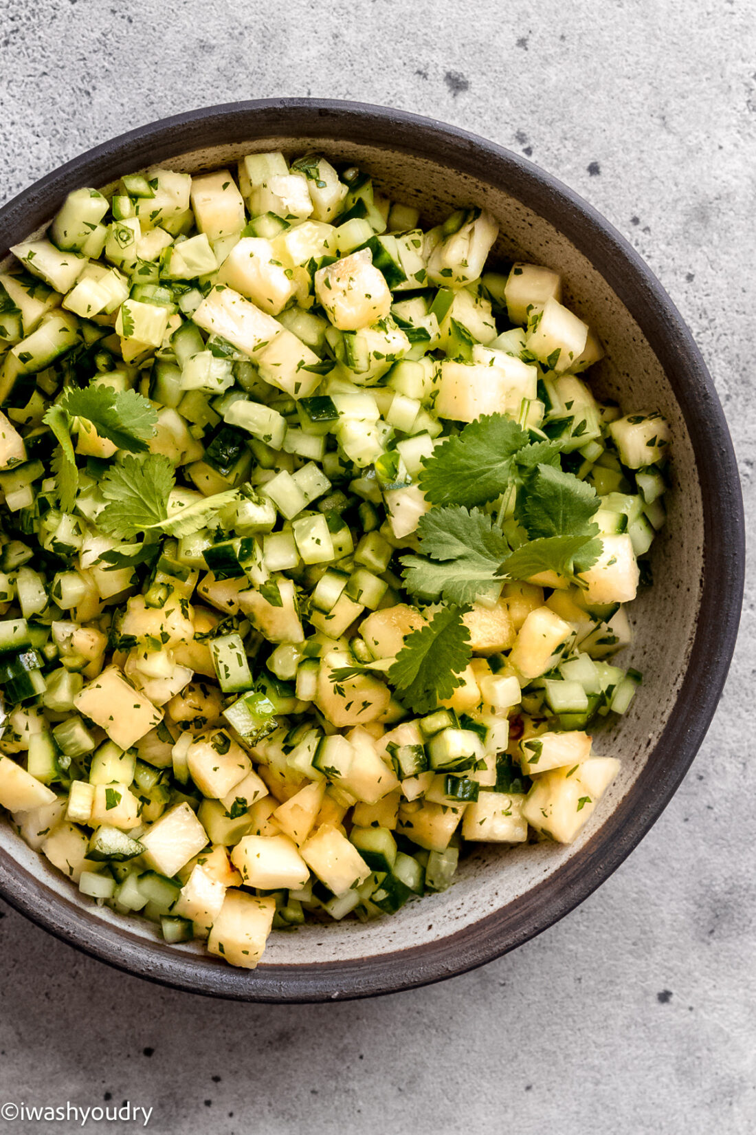 Cucumber pineapple salad in gray bowl. 