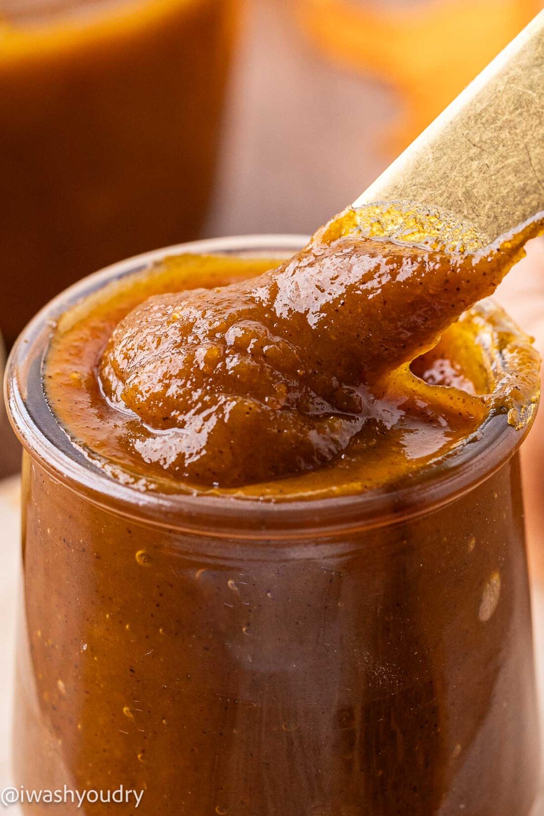 Cooked pumpkin butter in jar with spoon.