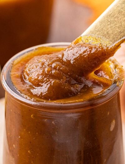 Cooked pumpkin butter in jar with spoon.