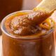 Cooked pumpkin butter in jar with spoon.