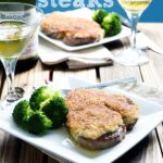 Two Plates on a table with Parmesan Crusted Steak and a side of broccoli