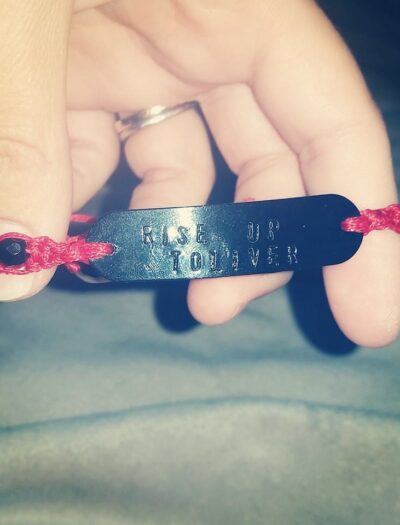 A close up of a bracelet that says "Rise Up Toliver"