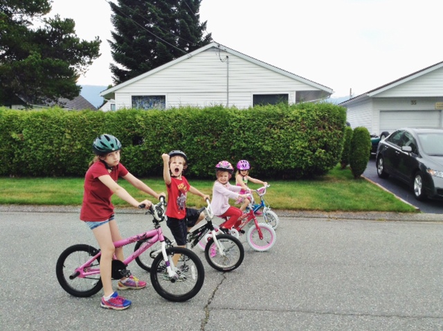 Four kids in the road on bikes riding