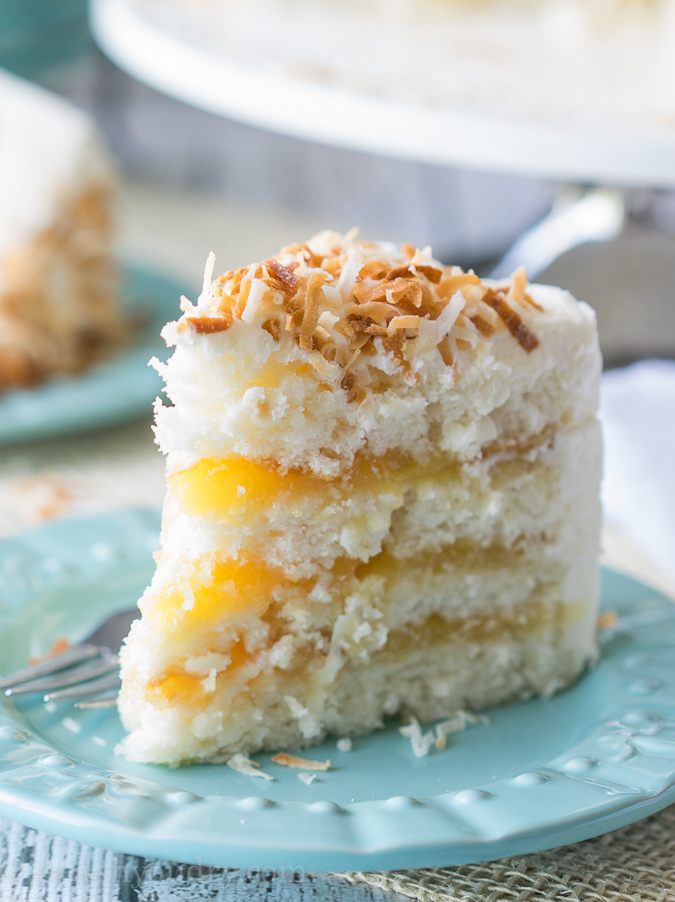 Slice of coconut cake with lemon filling on blue plate.