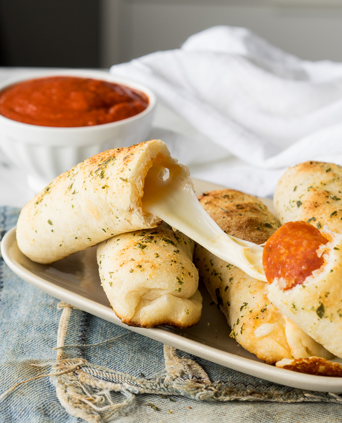 pizza stick cut in half with cheese pulling between.