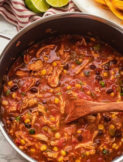 black pot filled with red chicken tortilla soup with black beans.