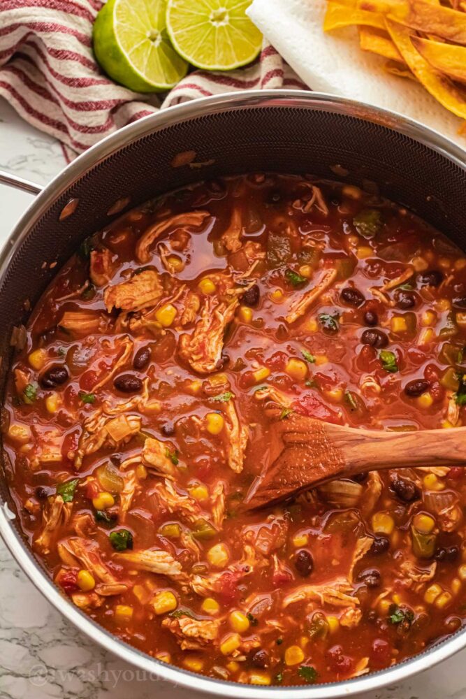 black pot filled with red chicken tortilla soup with black beans.