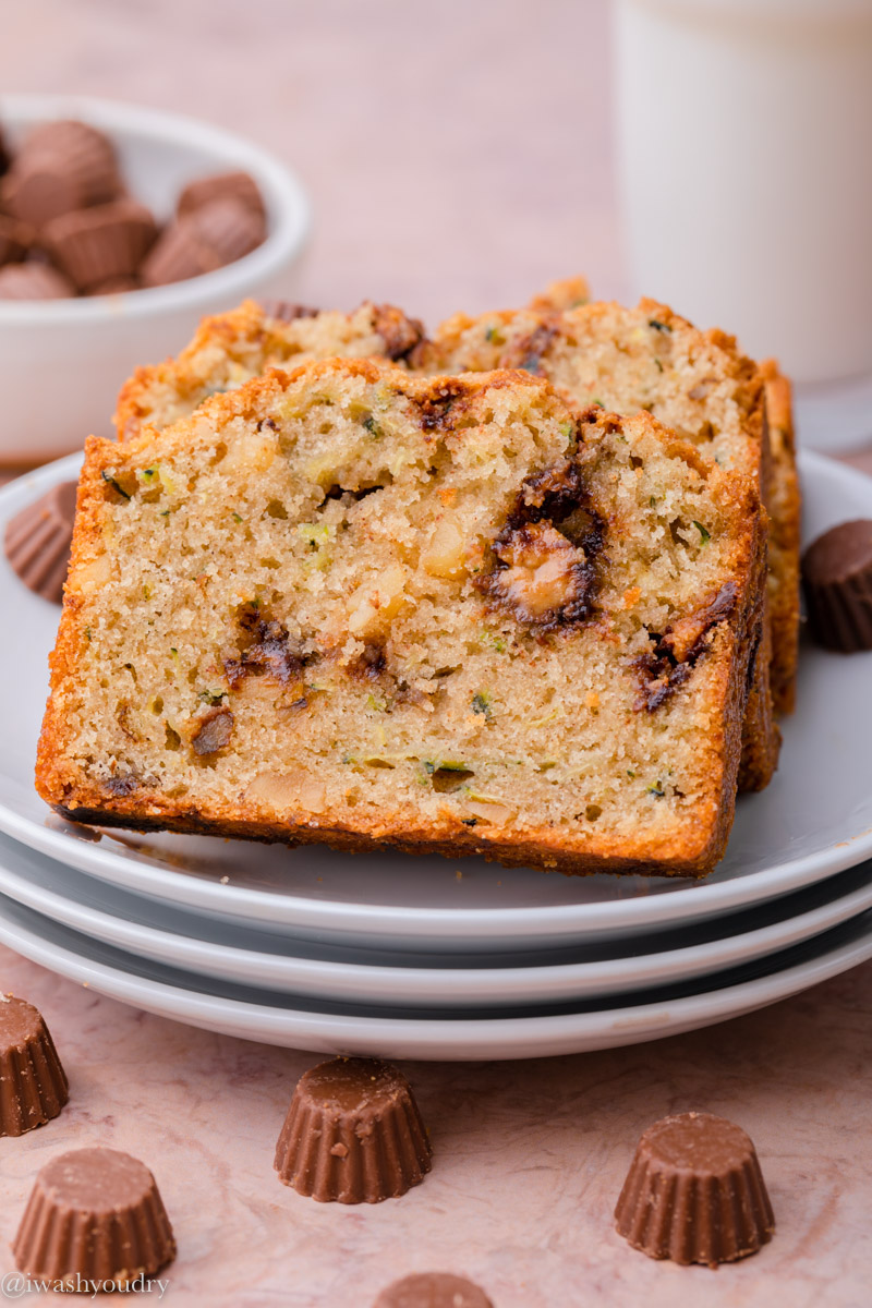 Slices of Chocolate Peanut Butter Cup Zucchini Bread on stack of white plates with mini peanut butter cups. 