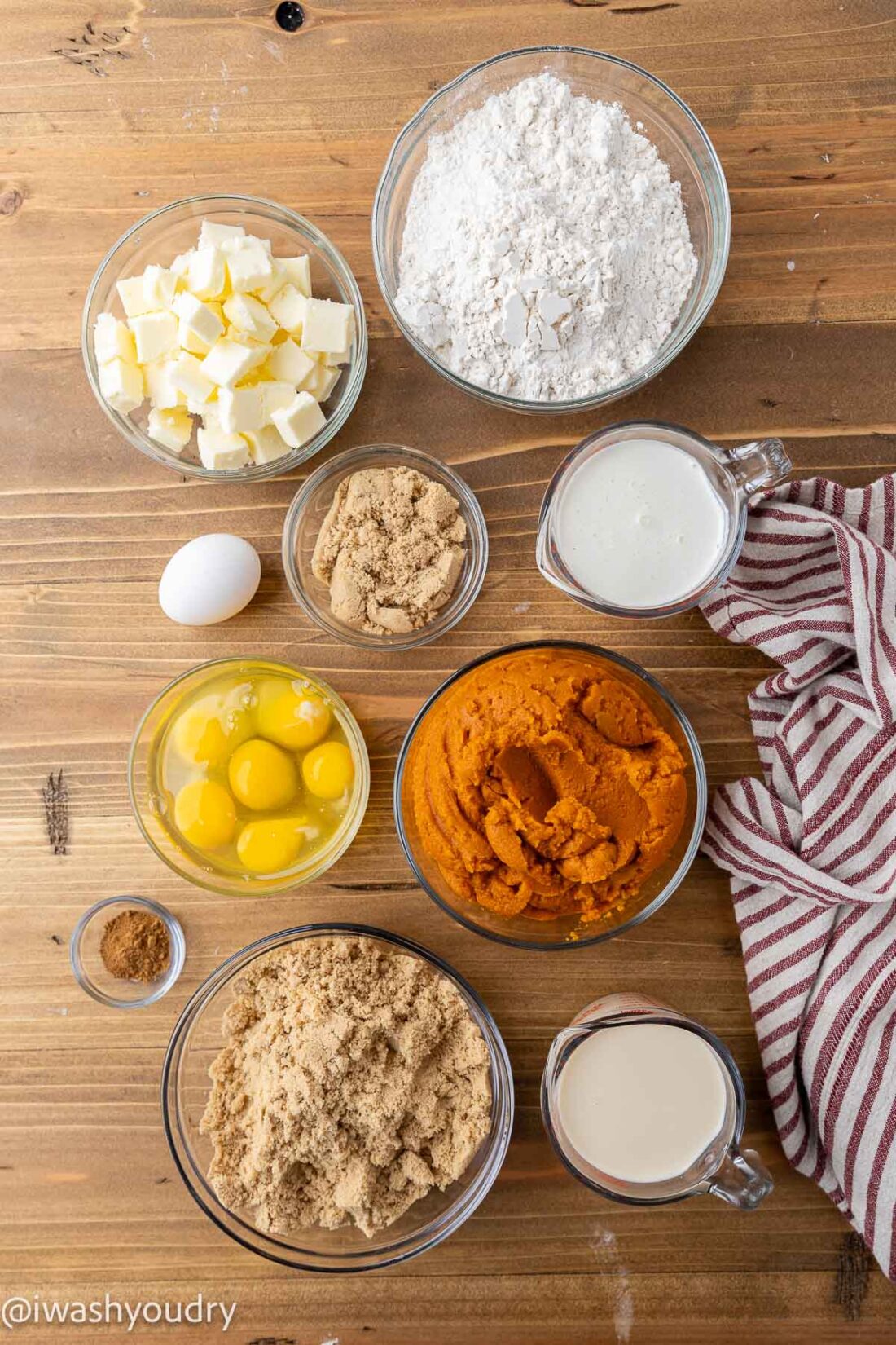 Ingredients for pumpkin pie bars in glass bowls on wood surface. 