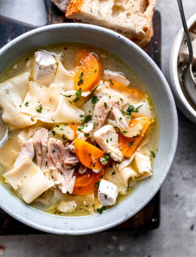 Cooked turkey noodle soup in white bowl.