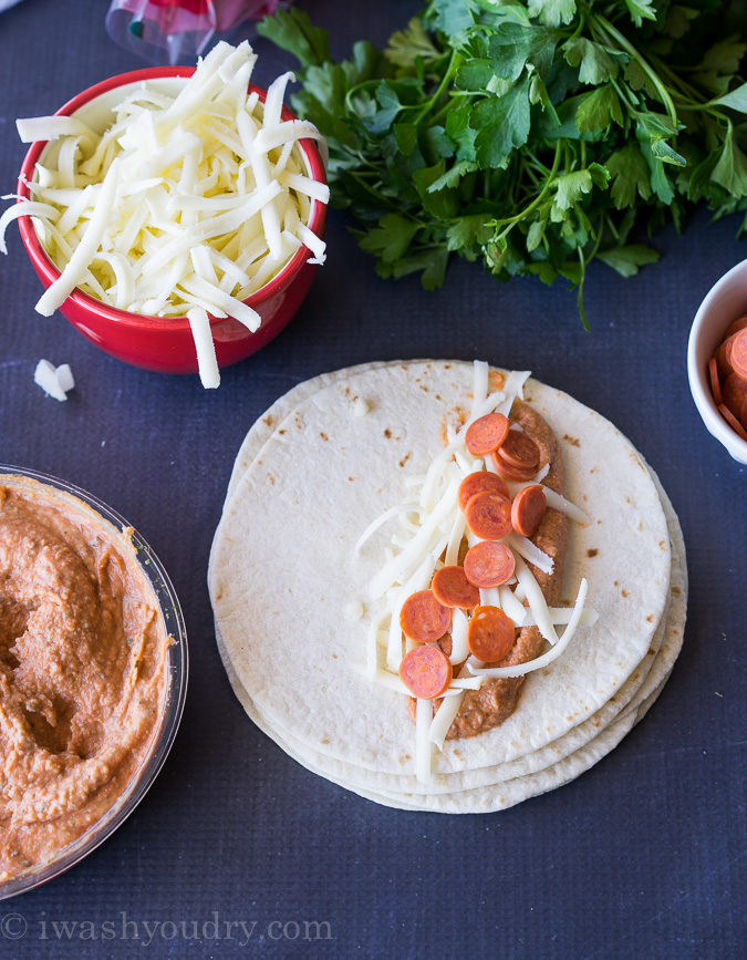 These Pizza Hummus Taquitos are a cheesy, crispy baked snack or appetizer that my kids go nuts for! They're so easy to make too! 