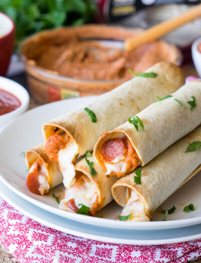 These Pizza Hummus Taquitos are a cheesy, crispy baked snack or appetizer that my kids go nuts for! They're so easy to make too!