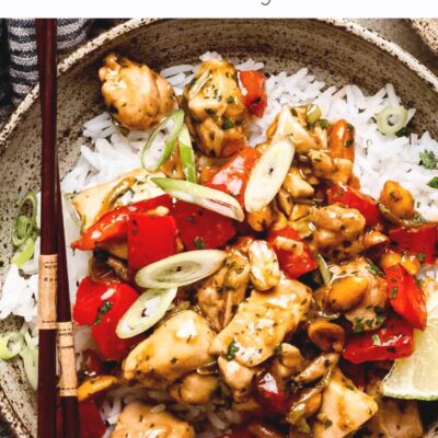 Cooked cilantro chicken stir fry in a bowl of rice with chopsticks.