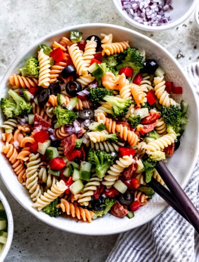 pasta salad recipe in bowl with wooden spoon.