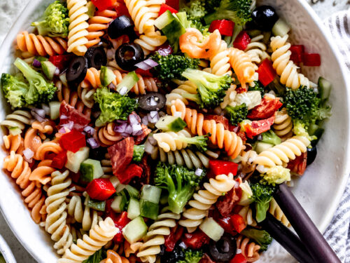 pasta salad recipe in bowl with wooden spoon.