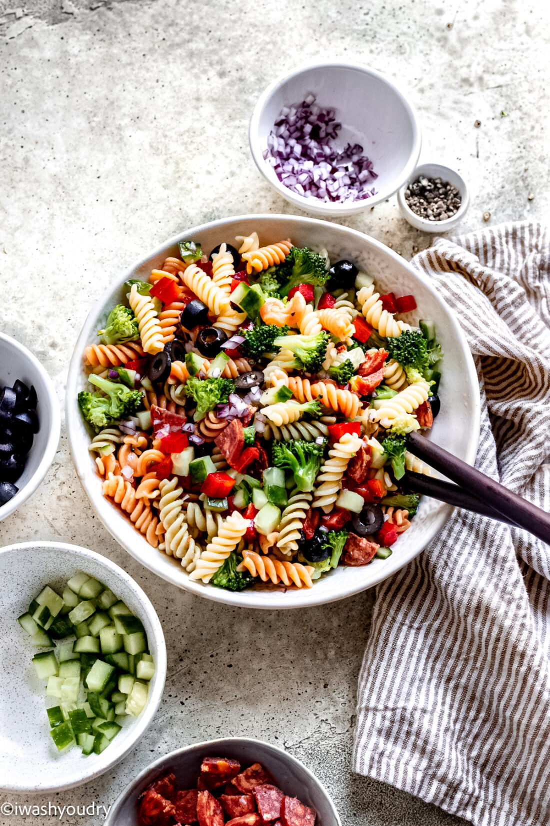 bowl of italian pasta salad with wooden spoon for party.