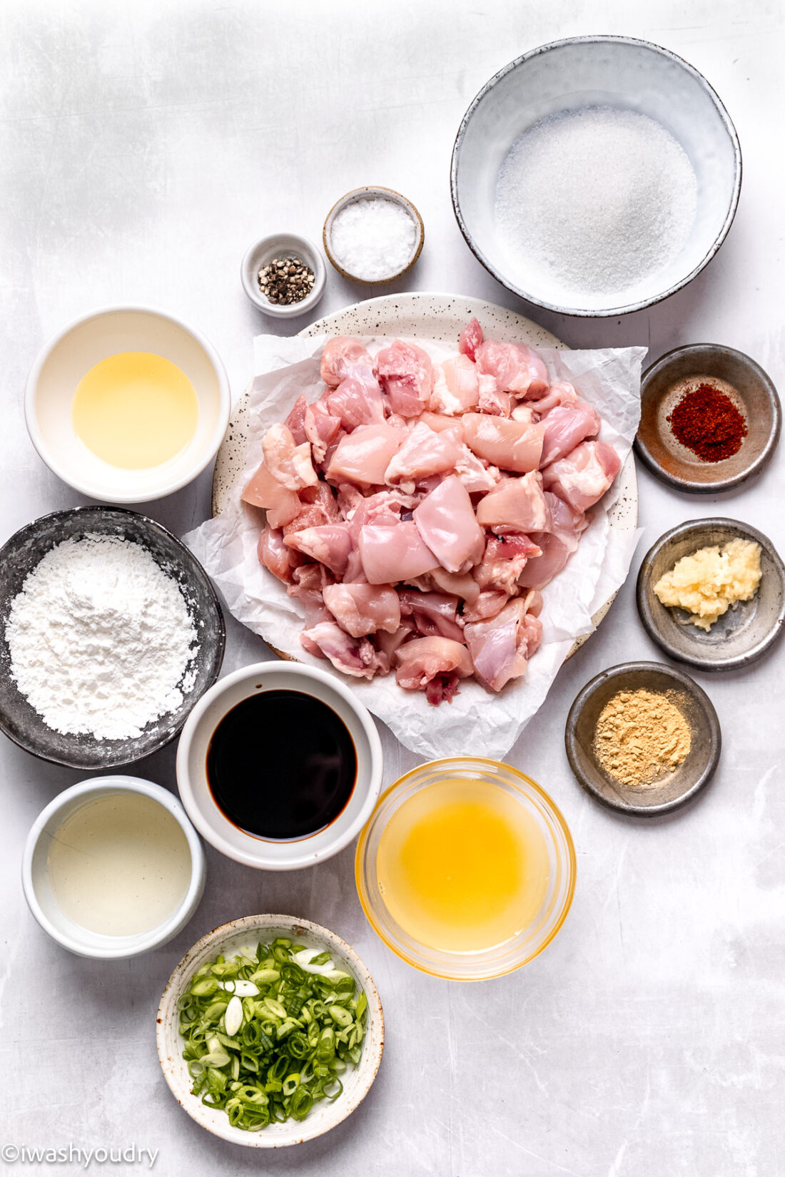 Ingredients for General Tso's chicken in glass bowls on marble countertop. 