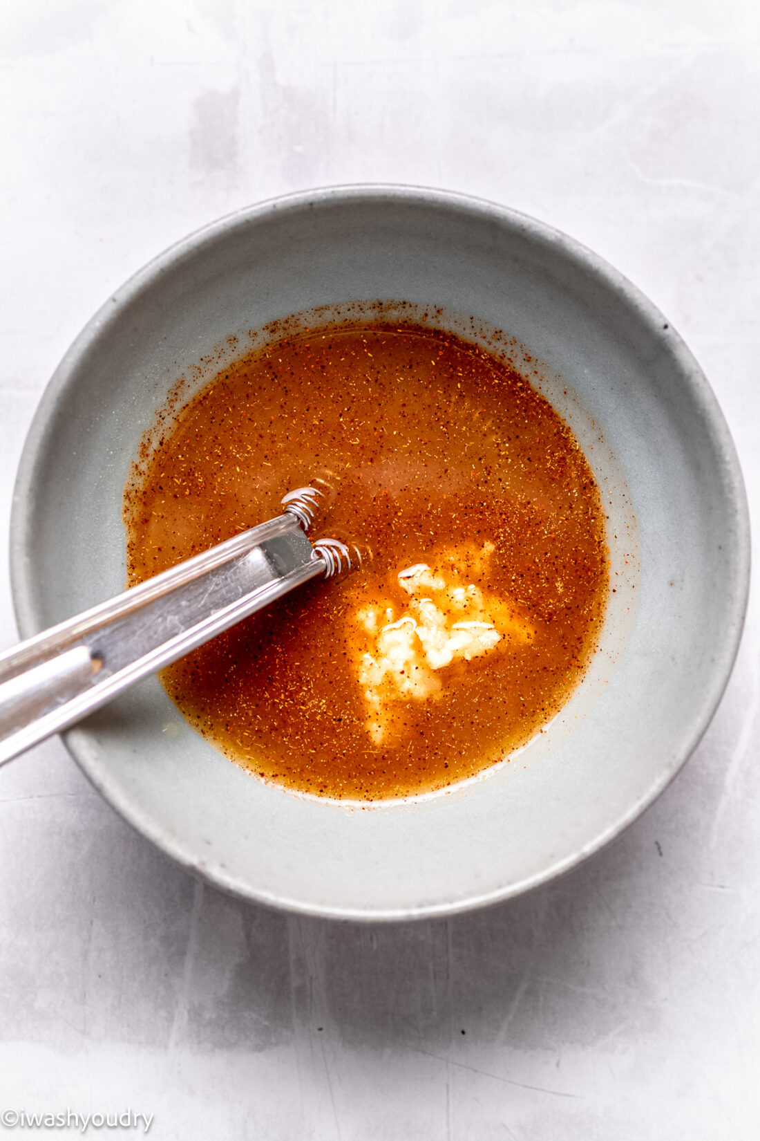 Sauce for General Tso's chicken in white owl with spoon. 