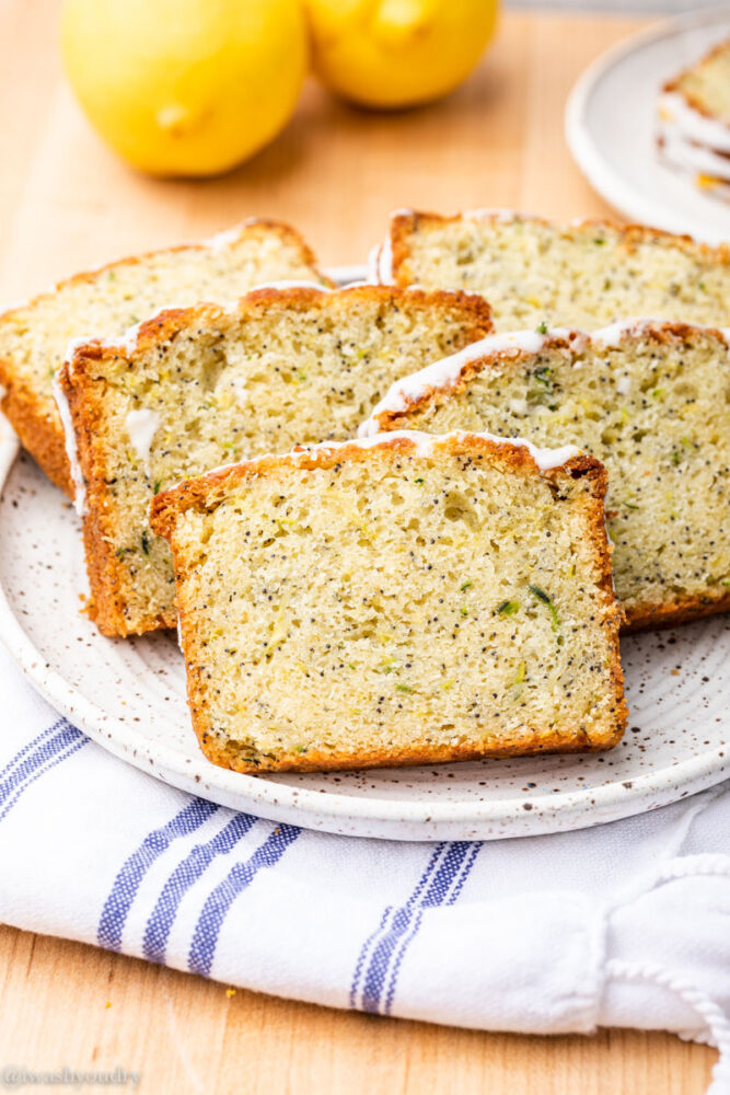 slices of zucchini bread on white plate with lemons.