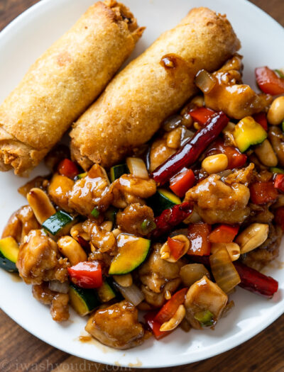 chicken and zucchini in sauce with egg rolls on white plate