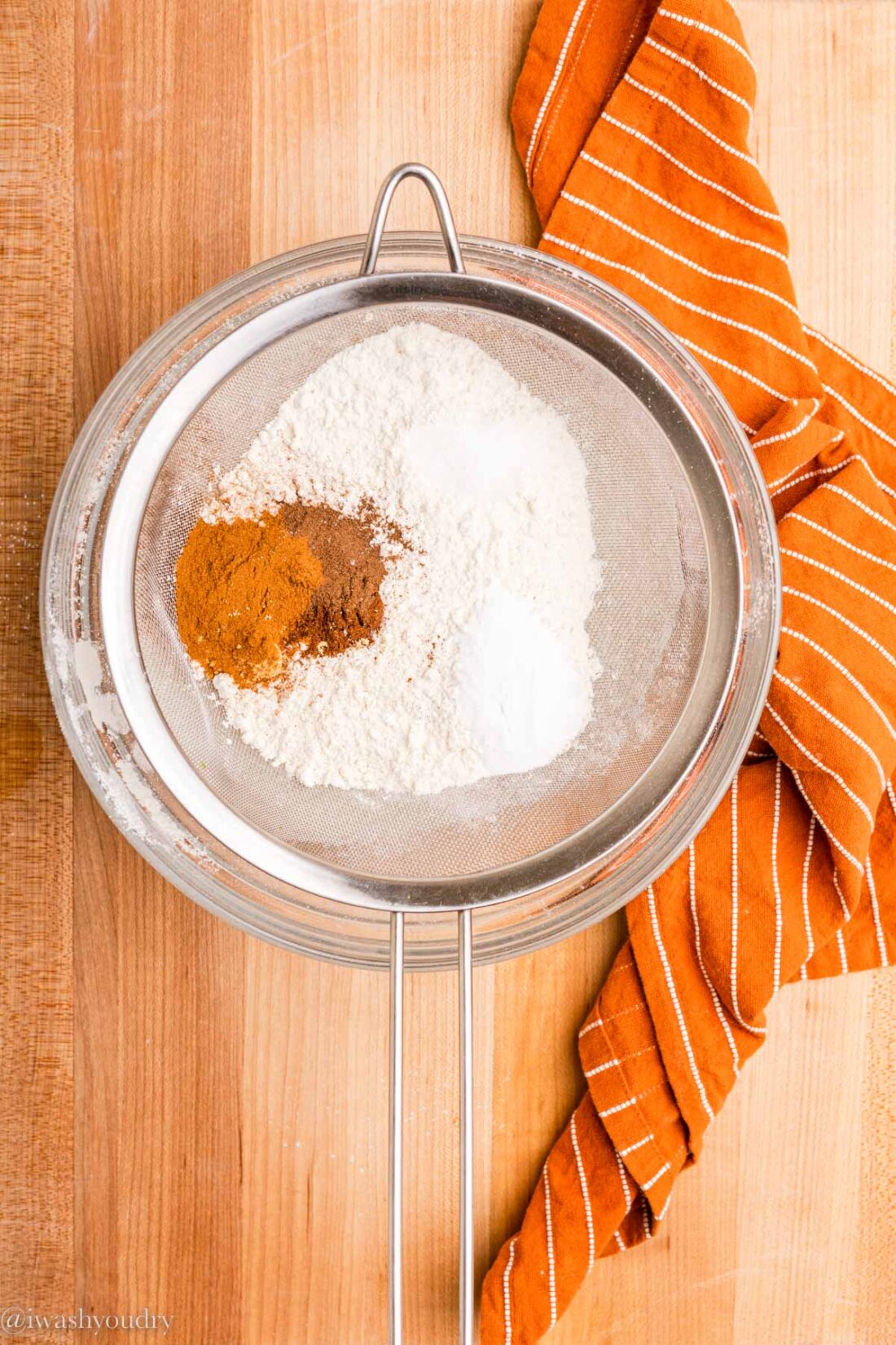 Dry ingredients for pumpkin chocolate chip bread in sifter in glass bowl. 