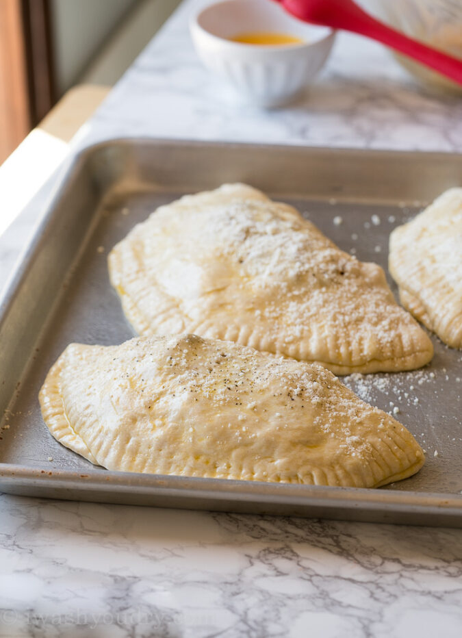 Brush the tops of each calzone with a simple egg wash, sprinkle with black pepper and grated parmesan cheese. 