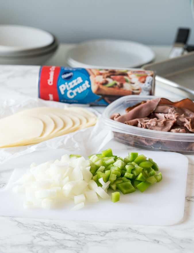 Chop up some green bell peppers and onions to sauté for these quick and easy Philly Cheese Steak Pizza Sticks!