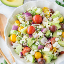 A bowl of salad, with cucumbers, avocado and tomatoes