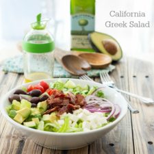 A bowl of California Greek Salad on a wooden surface