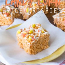 A square of a rice crispy treat on a plate, topped with candy corn and melted white chocolate