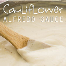 A close up of a white sauce being stirred with a wooden spoon