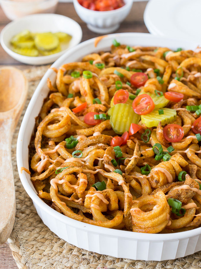 A casserole dish of pasta with hamburger, pickles, tomatoes